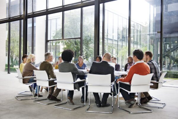 Groupe de professionnels autour d’une table en réunion, discutant en entreprise, ambiance moderne et conviviale. Étude de cas conduite du changement en contexte organisationnel.