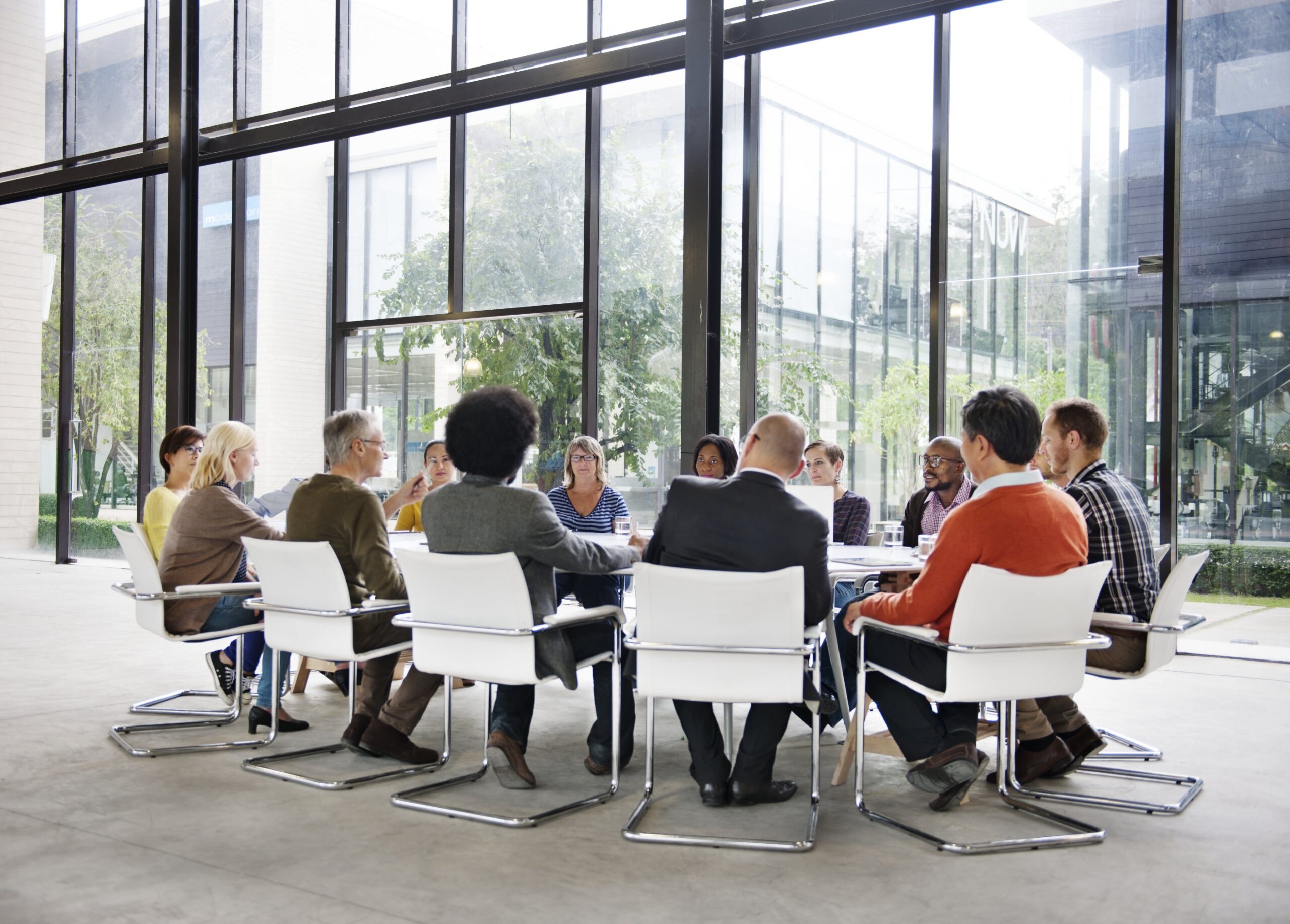 Groupe de professionnels autour d’une table en réunion, discutant en entreprise, ambiance moderne et conviviale. Étude de cas conduite du changement en contexte organisationnel.