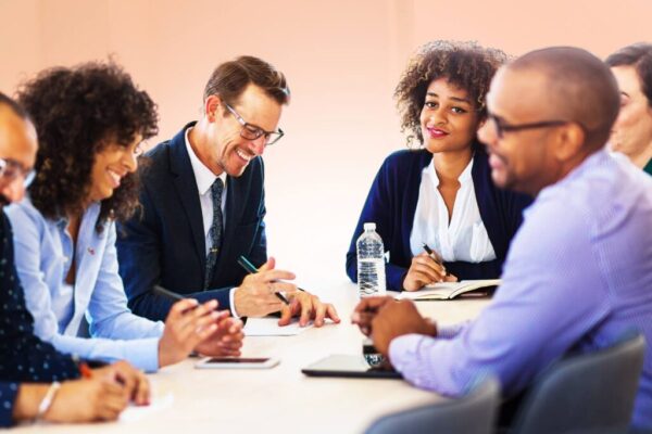 Groupe professionnel en réunion, échanges amicaux et collaboration autour d’un document, représentant le soft skills manager de demain